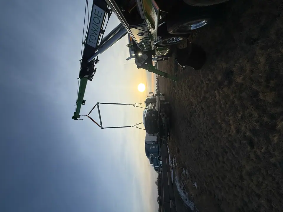 Rotator lifting a wrecked vehicle at sunset